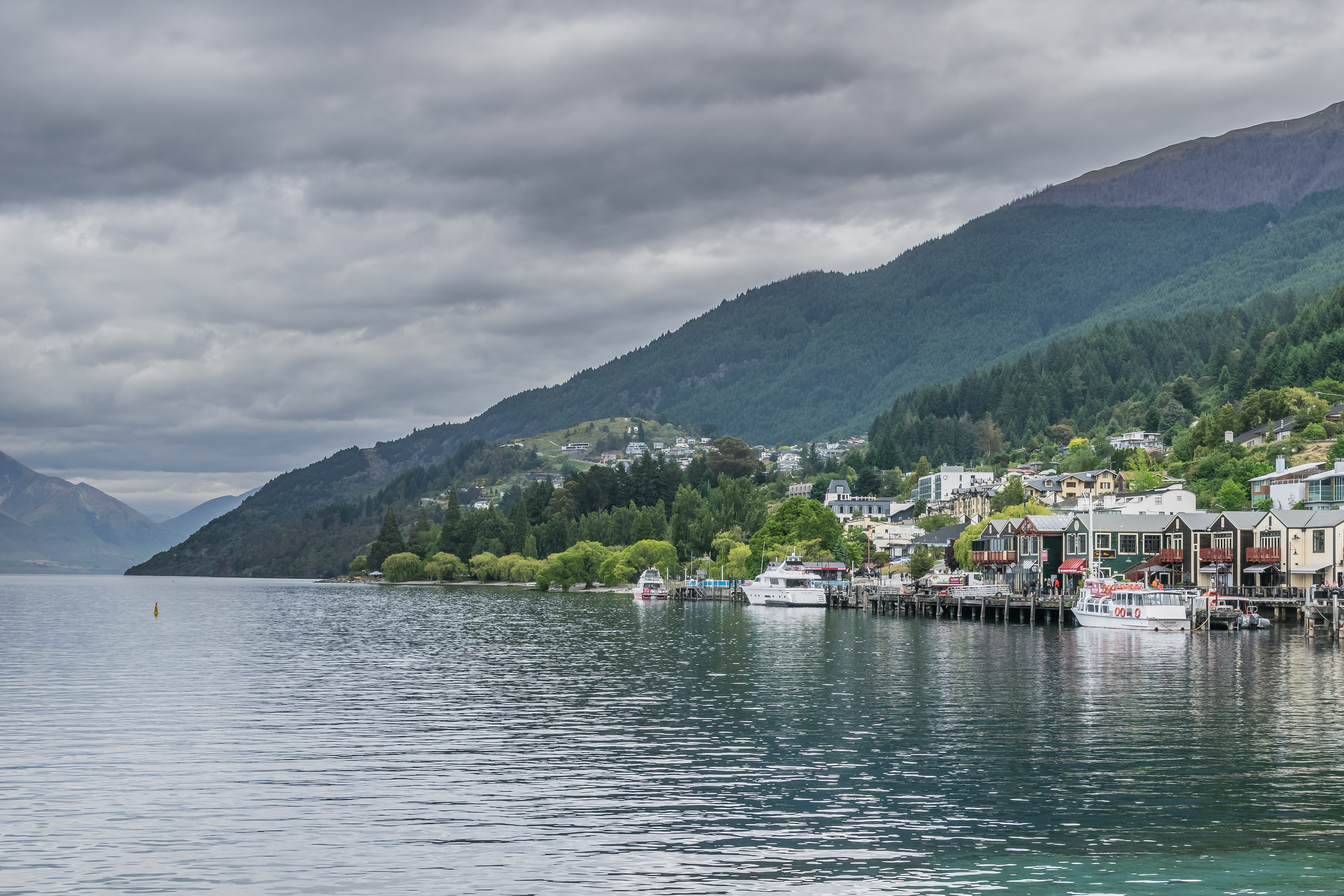 Overcast Lake Wakatipu waterfront and Queenstown mountains