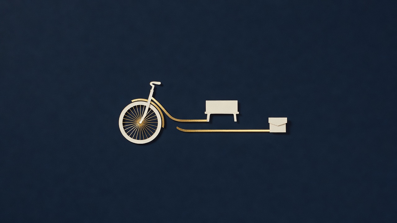 Paper-cut still life of the front of a bicycle with two gold ribbons running from it to a small bench and a folded paper parcel, on navy