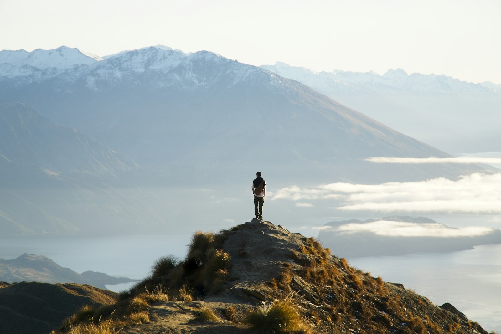 Solo hiker on a New Zealand mountain ridge above the lake